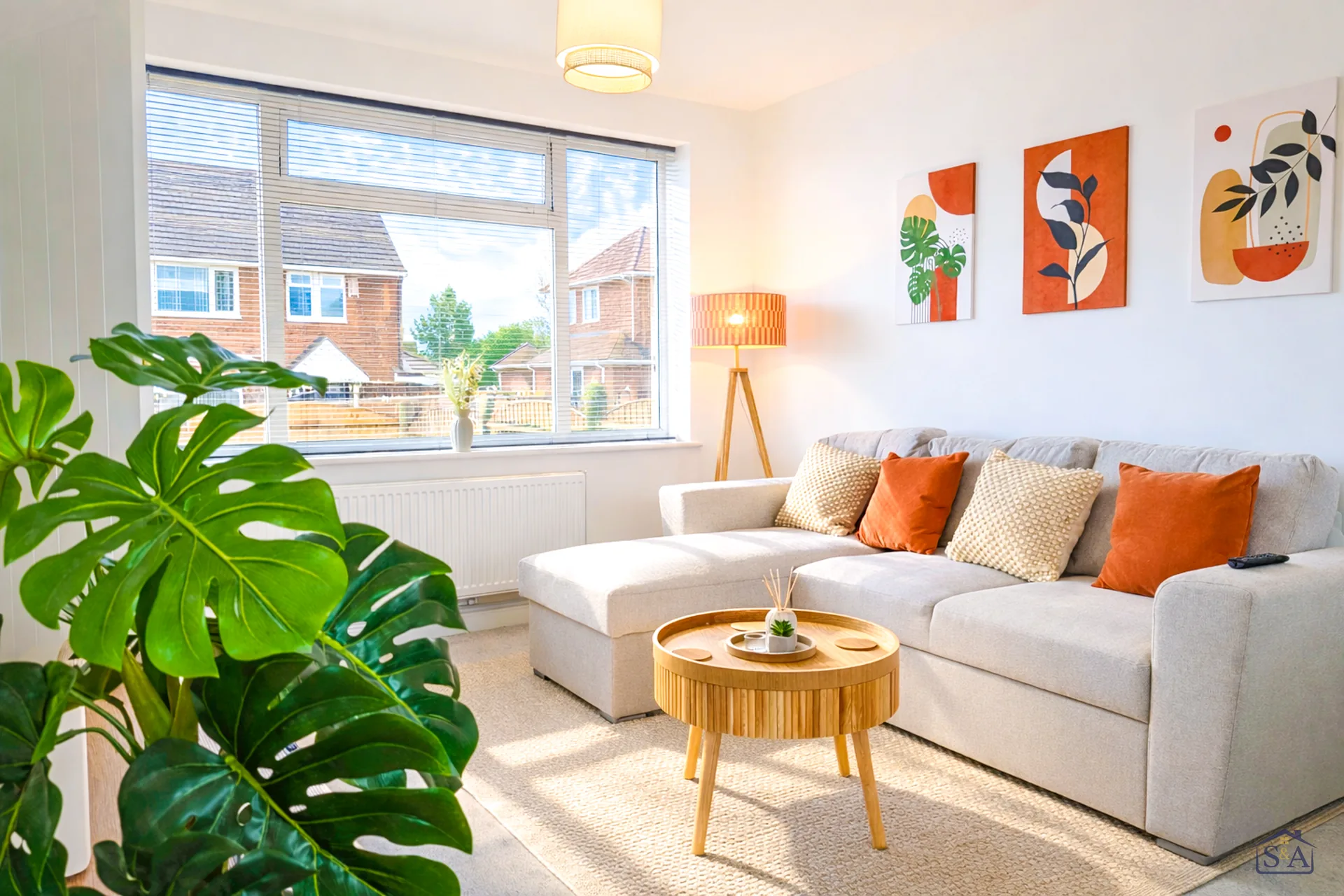 Bright S&A Stays living room with a large sofa and leafy plants