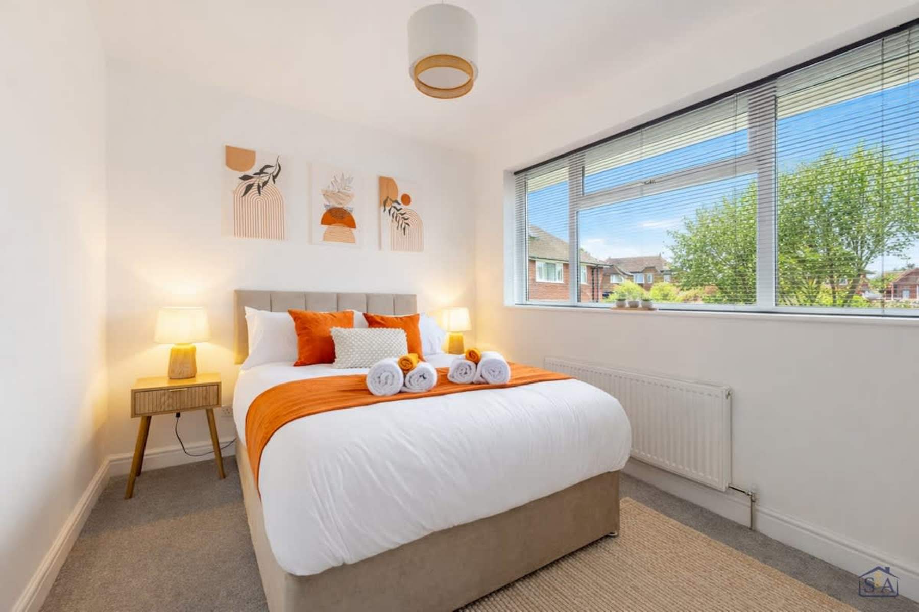 Comfortable double bedroom dressed in white and warm orange